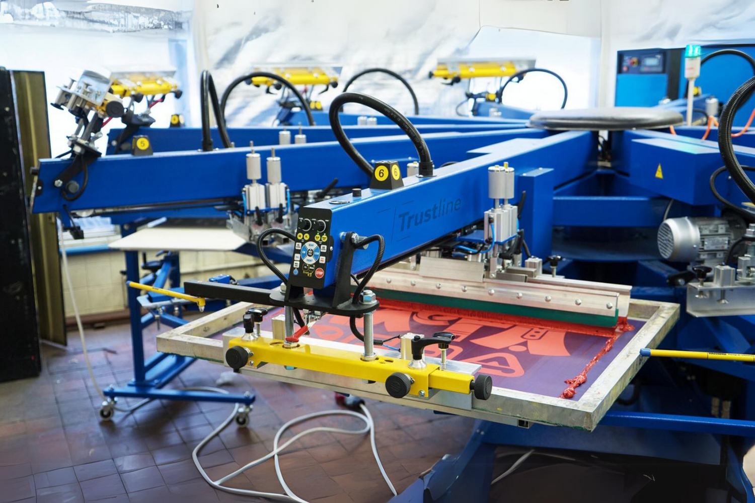 Advanced screen printing machine by Trustline Enterprises in a production facility, creating custom printed materials.