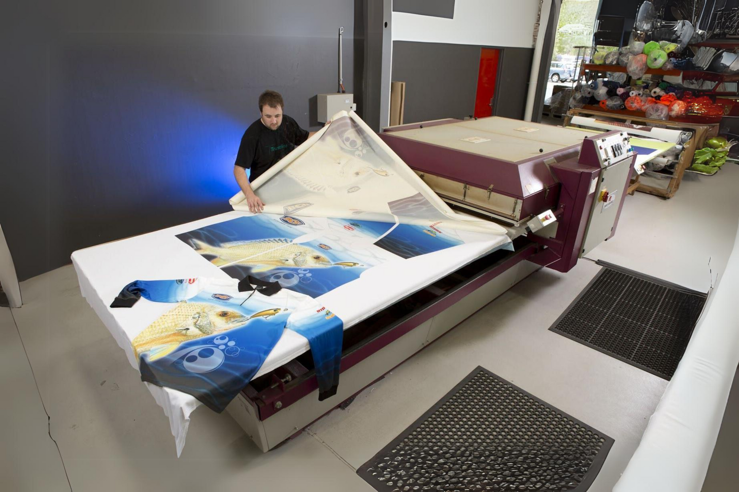 Worker operating a large format printing machine by Trustline Enterprises, producing high-quality custom banners.