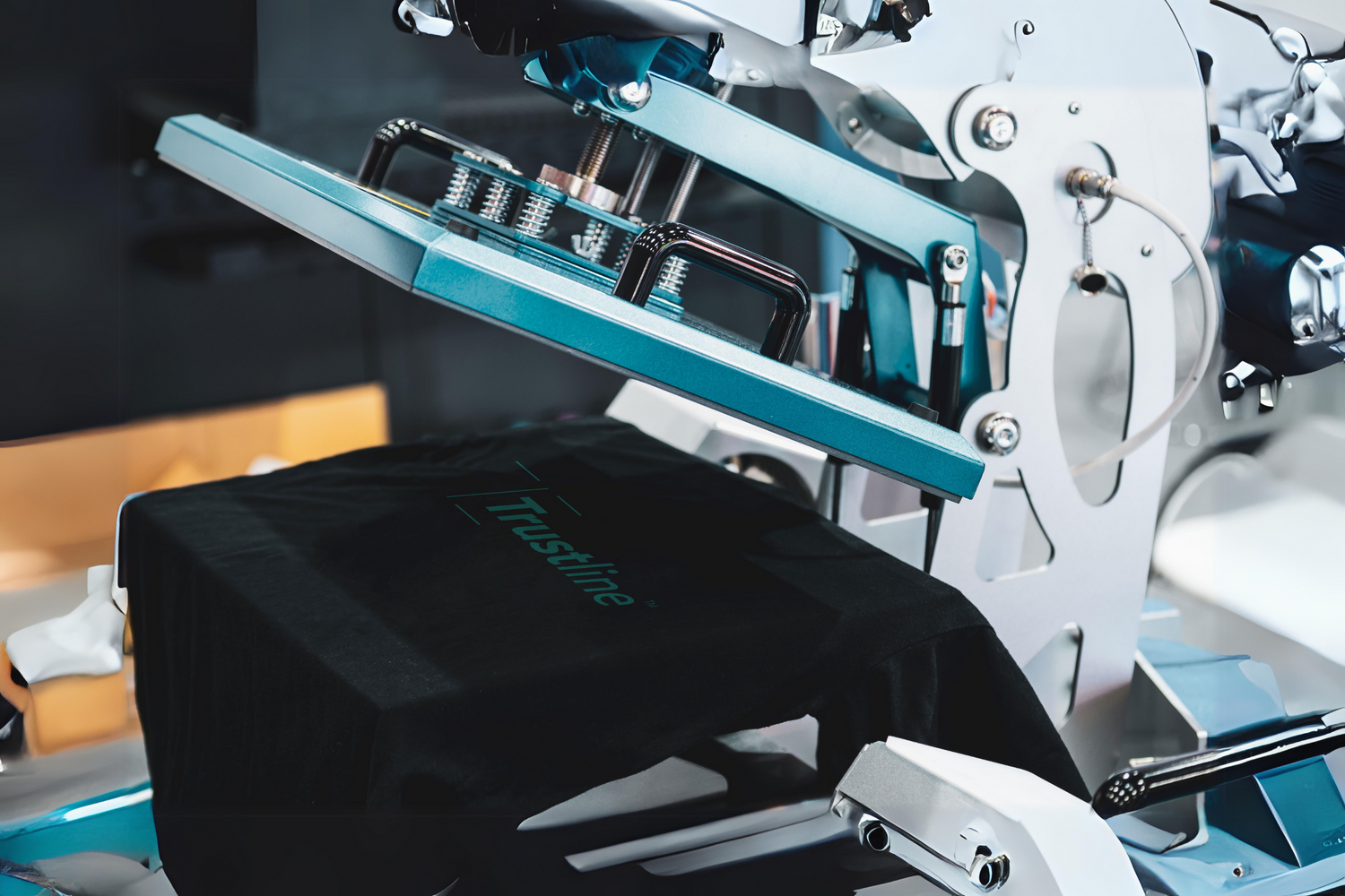 Close-up of a Trustline Enterprises printing machine, producing a custom design on a black t-shirt.