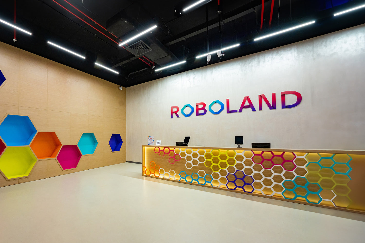 The colorful and modern reception area of RoboLand, with a hexagonal design theme on the walls and front desk, emphasizing the innovative and playful atmosphere of this edutainment destination.