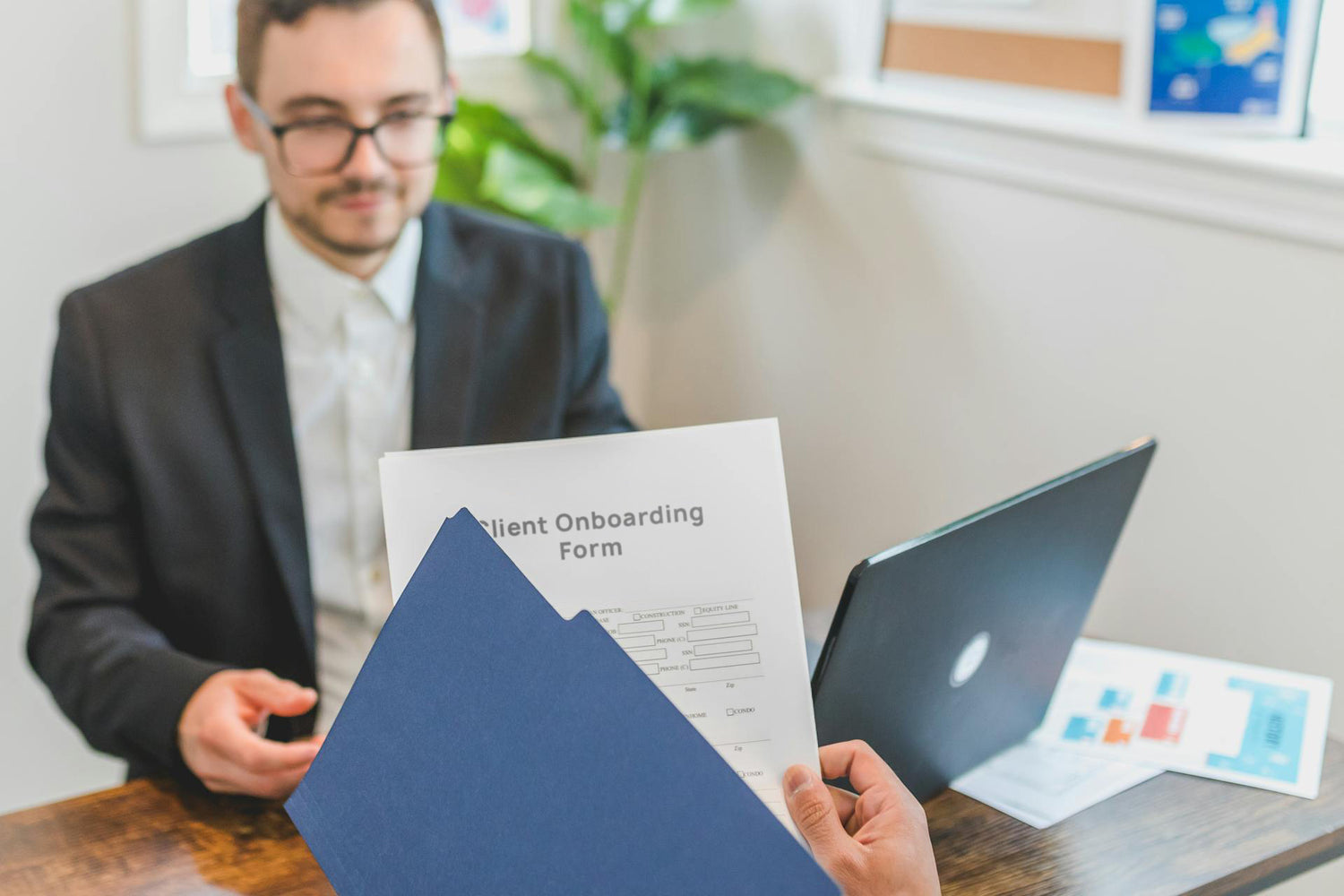 Business professional explaining something on a laptop to a colleague in a bright office setting.