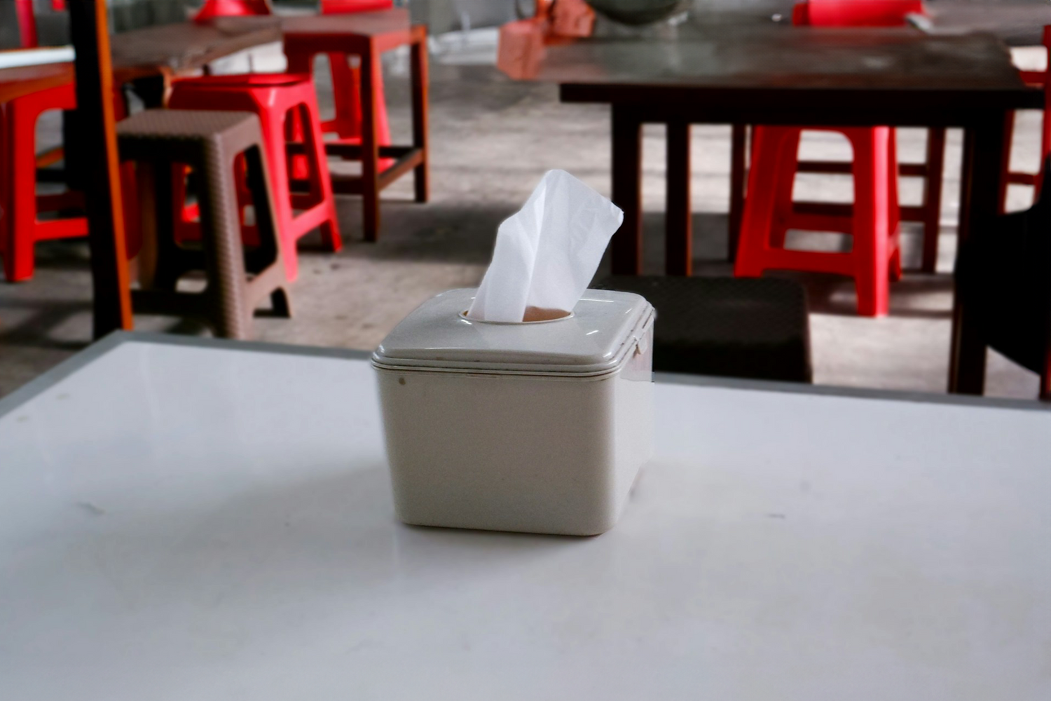 quare tissue holder on a table in a cafeteria setting, demonstrating Trustline Enterprises' practical and high-quality paper products for foodservice and hospitality industries.