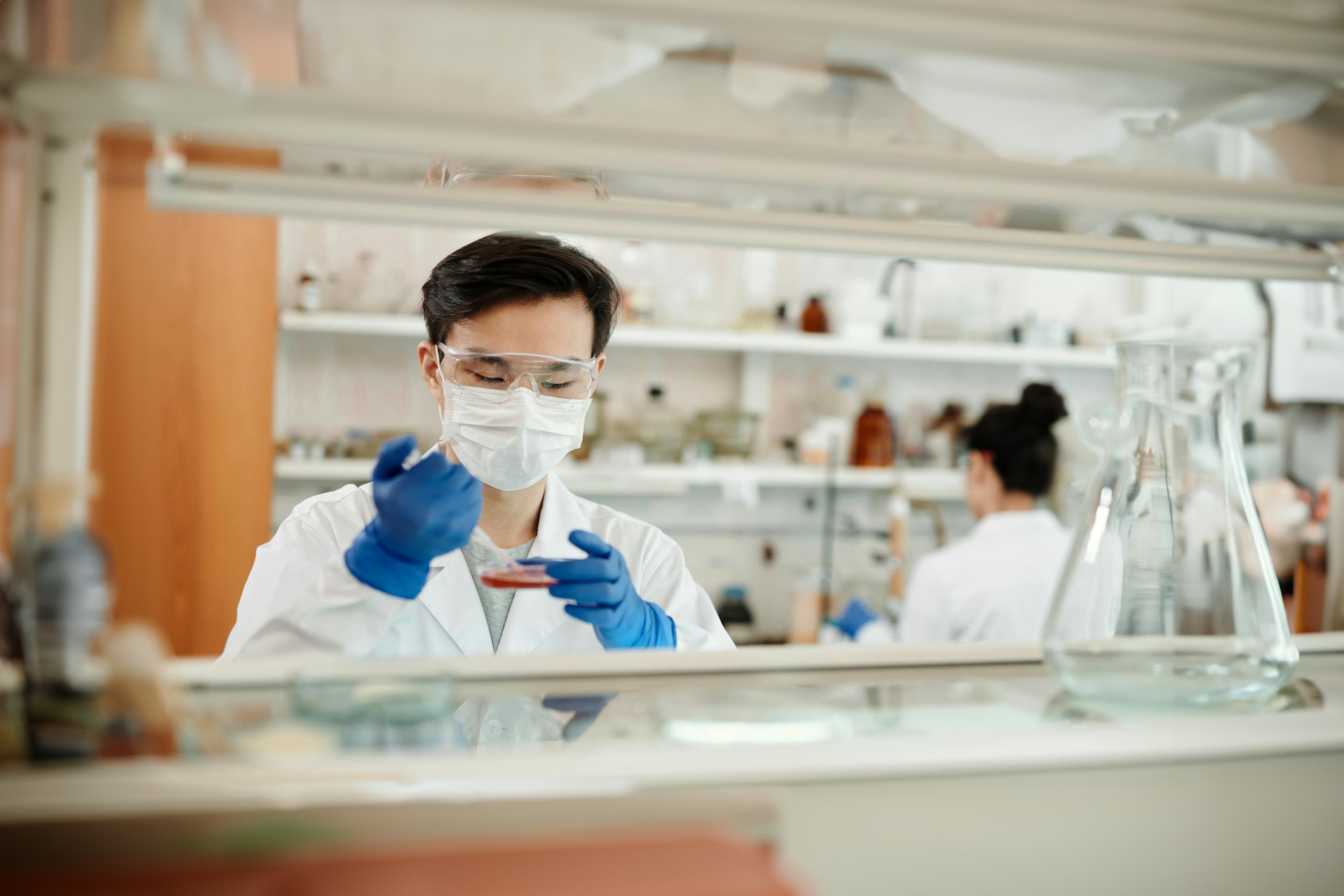 Scientist in a laboratory wearing protective gear and handling a petri dish, highlighting Trustline Enterprises' high-quality supplies and solutions for the healthcare and research industries.