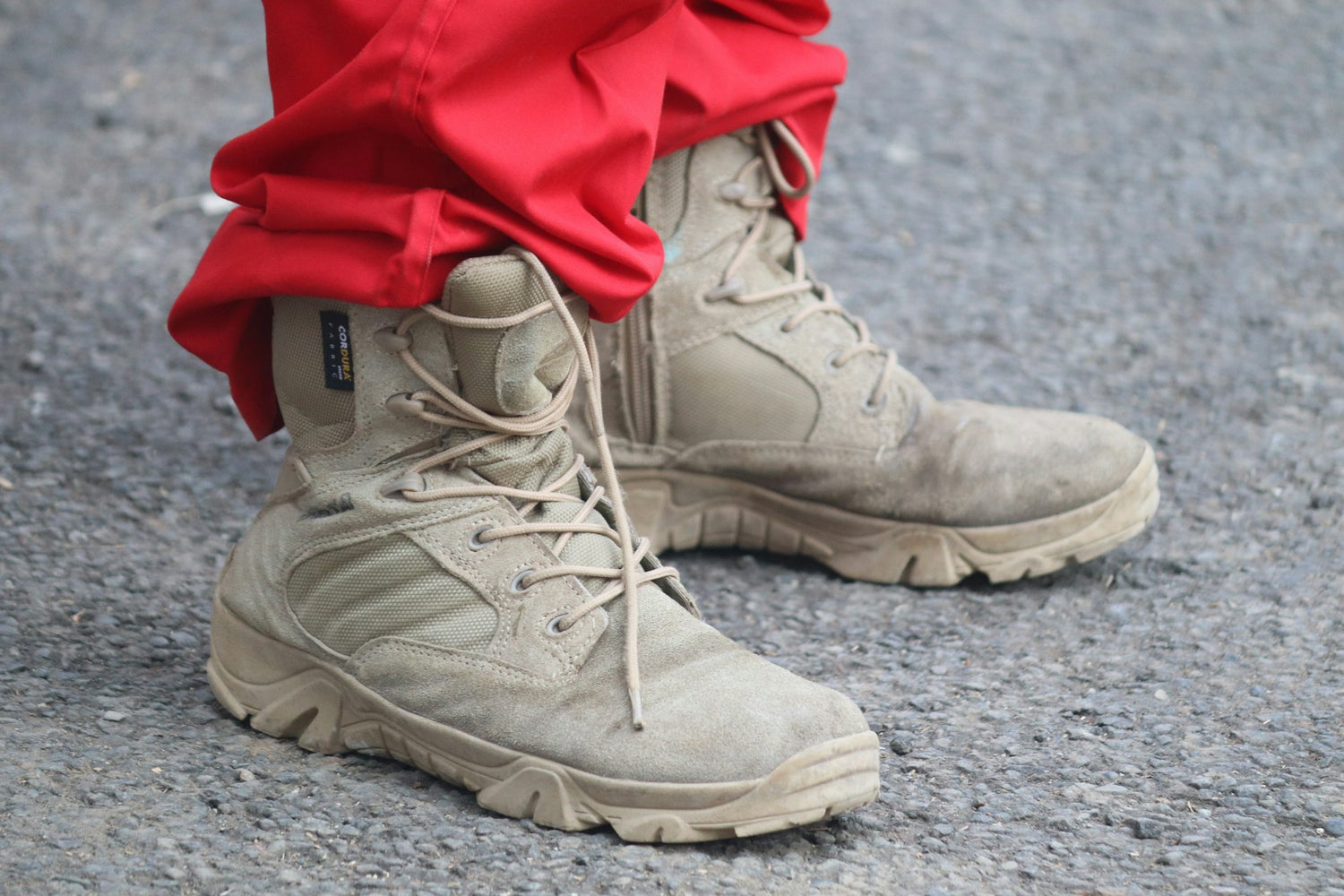 Close-up of durable work boots by Trustline Enterprises, worn by a worker in red protective pants.