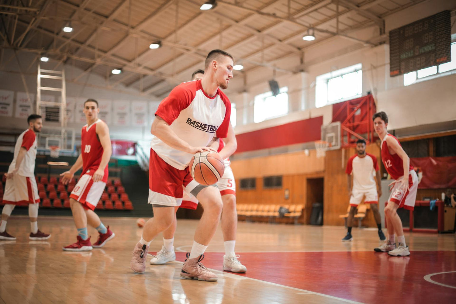 Basketball players wearing durable uniforms by Trustline Enterprises, actively playing in an indoor basketball court.