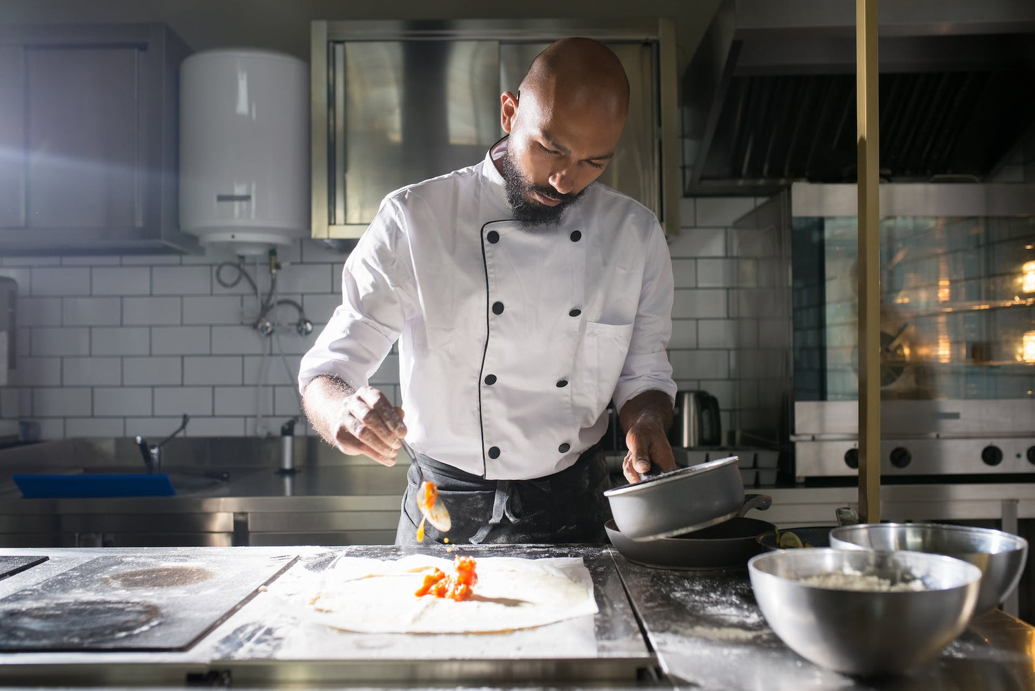 Chef in a commercial kitchen preparing a dish, exemplifying Trustline Enterprises' durable uniforms and high-quality supplies for the foodservice industry.