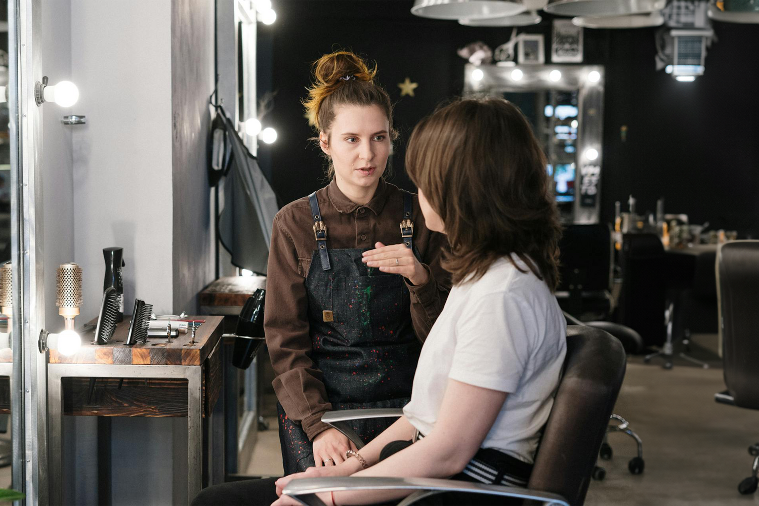 Hairdresser in a durable uniform by Trustline Enterprises, consulting with a customer in a modern salon.